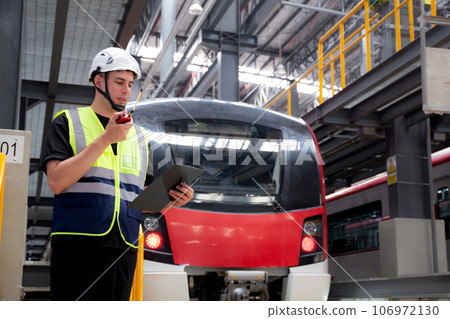 Young caucasian engineer man or worker hold clipboard for looking and checking electric train. 106972130