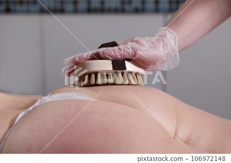 Body massage with brush with natural bristles.Body care. Exfoliation or peeling in beauty salon. Body massage with brush with natural bristles.Body care. Exfoliation or peeling in beauty salon. 106972148