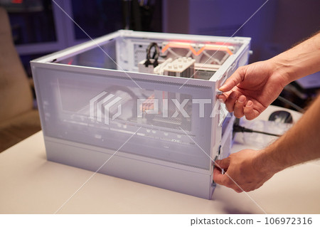 Close-up of technician's hand assembling personal computer. Close-up of technician's hand assembling personal computer. 106972316