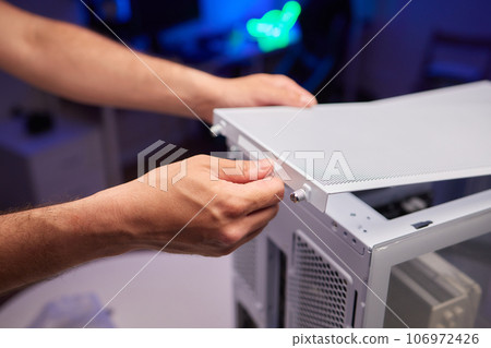 Close-up of technician's hand assembling personal computer. Close-up of technician's hand assembling personal computer. 106972426