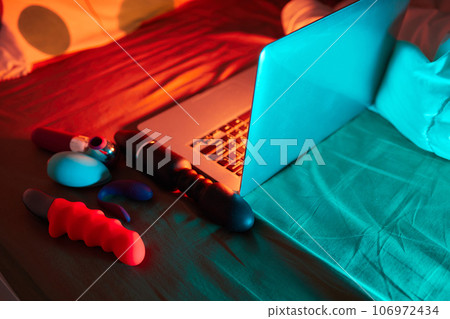 toys for sex on a laptop on a bright neon background. 106972434