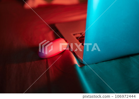 toys for sex on a laptop on a bright neon background. 106972444