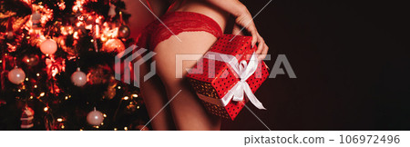 sexy buttocksof a girl in underwear with a gift box in her hands at the Christmas tree on New Year 106972496