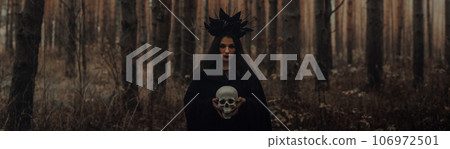 black terrible witch with a skull in the hands of a dead man black terrible witch with a skull in the hands of a dead man 106972501