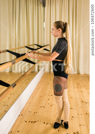 Young woman ballerina stretching and training at barre in dance studio - ballet and dancer concept Young woman ballerina stretching and training at barre in dance studio - ballet and dancer concept 106972600