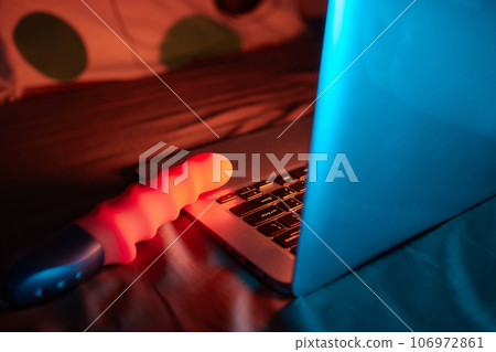 toys for sex on a laptop on a bright neon background. 106972861