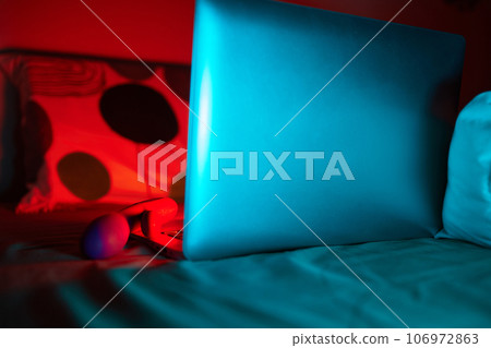 toys for sex on a laptop on a bright neon background. 106972863