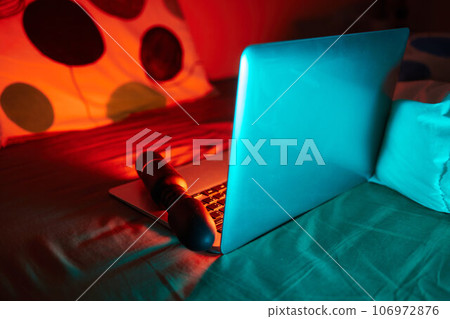 toys for sex on a laptop on a bright neon background. 106972876