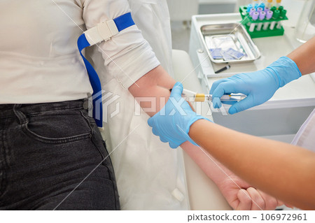 A swab is pressed onto the injection site during the blood collection. A swab is pressed onto the injection site during the blood collection. 106972961