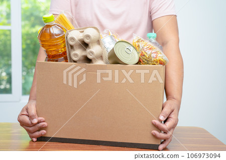 Volunteers putting various dry food in donation box for help people. Volunteers putting various dry food in donation box for help people. 106973094