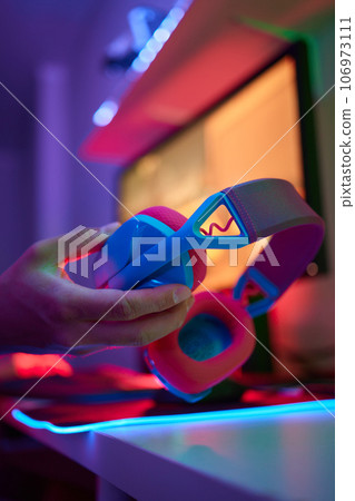 A young guy gets a phone call during an online video game, he takes off his headphones and goes to talk. A young guy gets a phone call during an online video game, he takes off his headphones and goes to talk. 106973111