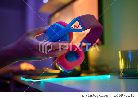 A young guy gets a phone call during an online video game, he takes off his headphones and goes to talk. 106973115