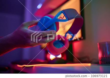 A young guy gets a phone call during an online video game, he takes off his headphones and goes to talk. 106973121