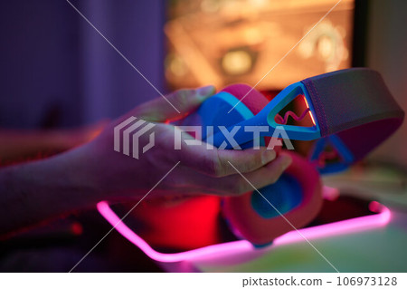 A young guy gets a phone call during an online video game, he takes off his headphones and goes to talk. 106973128