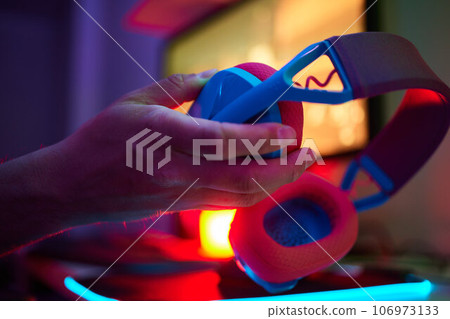 A young guy gets a phone call during an online video game, he takes off his headphones and goes to talk. A young guy gets a phone call during an online video game, he takes off his headphones and goes to talk. 106973133