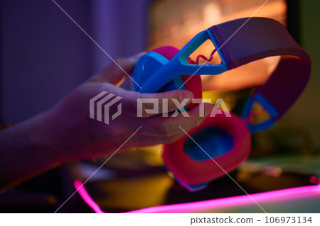 A young guy gets a phone call during an online video game, he takes off his headphones and goes to talk. A young guy gets a phone call during an online video game, he takes off his headphones and goes to talk. 106973134