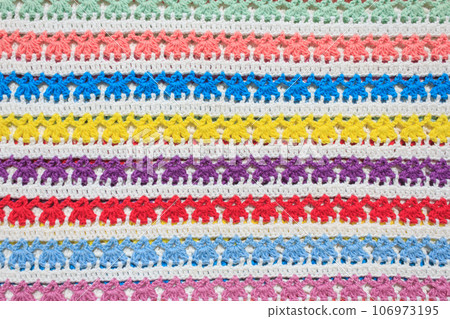 Background crocheted fabric, pattern of multi-colored rows handmade. Knitted striped plaid in a bright color. 106973195