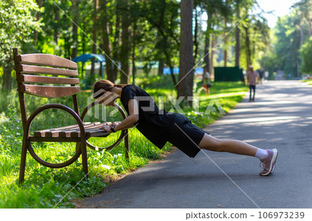 Beautiful young sporty woman in black t-shirt, black shorts and pink trainers warming up exercising triceps and chest Beautiful young sporty woman in black t-shirt, black shorts and pink trainers warming up exercising triceps and chest 106973239