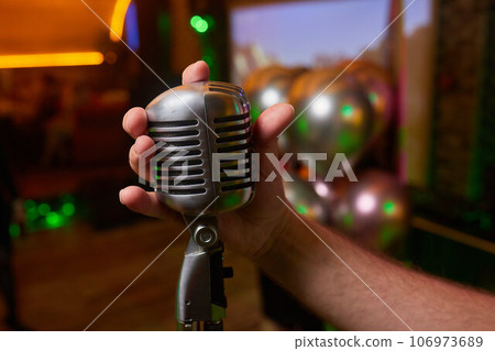 Retro Microphones on front stage in pub bar or restaurant. Classic sing a song in evening and night show concert light bokeh background. Retro Microphones on front stage in pub bar or restaurant. Classic sing a song in evening and night show concert light bokeh background. 106973689