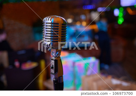 Retro Microphones on front stage in pub bar or restaurant. Classic sing a song in evening and night show concert light bokeh background. 106973700