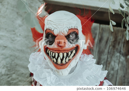evil redhead clown in front of the door of a house evil redhead clown in front of the door of a house 106974646