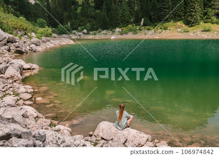 Woman Sitting on Rock by Mountain Lake in Durmitor 106974842