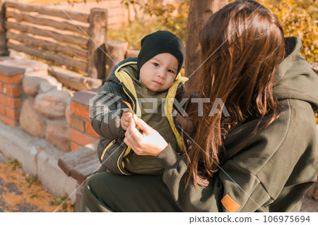 Cute little asian boy with mother outdoors. Happy child walking in autumn park. Toddler baby boy wears trendy jacket and hat. Autumn fashion. Stylish child outside. Cute little asian boy with mother outdoors. Happy child walking in autumn park. Toddler baby boy wears trendy jacket and hat. Autumn fashion. Stylish child outside. 106975694
