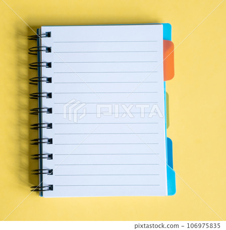 Opened notepad on a yellow background. Composition of writing to-dos for the day. The notebook lies on a plain background with space for writing.  106975835