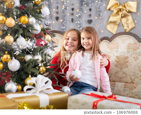 Two girls hugging on sofa in Christmas interior Two girls hugging on sofa in Christmas interior 106976008