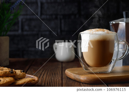 cappuccino in cup and geyser coffee maker on wooden table with black brick wall as background 106976115