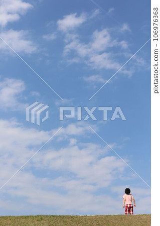 A child looking up at the blue sky 106976368