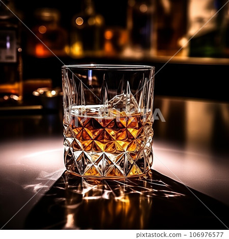 A glass of whiskey close-up. Product photography. Glass of old whiskey standing on a table in a luxury bar. Composition of whiskey cup in a dark office room. 106976577