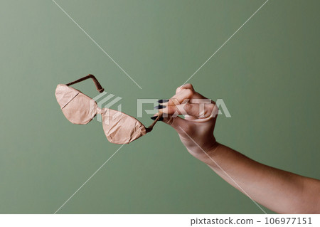 Female hand holds a brand new glasses wrapped in rustic beige craft paper. Black Friday shopping concept. 106977151