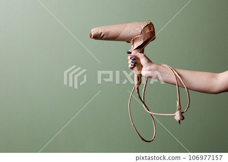 Female hand holds a brand new hair dryer wrapped in rustic beige craft paper. Black Friday concept. Female hand holds a brand new hair dryer wrapped in rustic beige craft paper. Black Friday concept. 106977157
