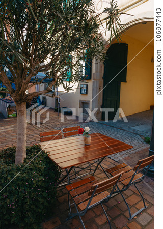 Empty cafe terrace with white table and chair. exterior of the cafe restaurant. interior Street cafe. Cozy street with flowers and French-style cafe table. Decor facade of coffeehouse with bike. Table 106977443