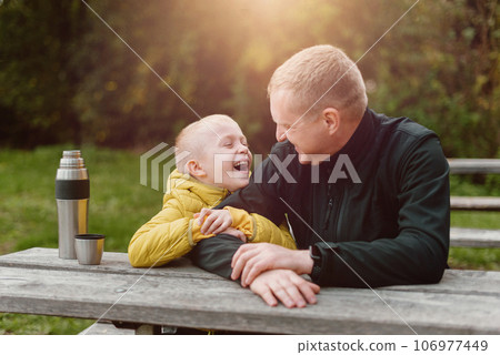 Happy Family: Father And Child Boy Son Playing And Laughing In Autumn Park, Sitting On Wooden Bench And Table. Father And Little Kid Having Fun Outdoors, Playing Together. Father And Son Sitting On A Happy Family: Father And Child Boy Son Playing And Laughing In Autumn Park, Sitting On Wooden Bench And Table. Father And Little Kid Having Fun Outdoors, Playing Together. Father And Son Sitting On A 106977449