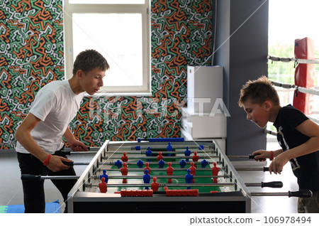 Active recreation in the game room, children play table football. 106978494