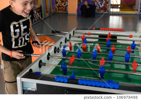 Active recreation in the game room, children play table football. Active recreation in the game room, children play table football. 106978498