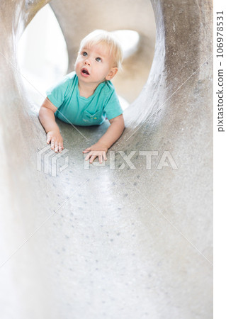 Child playing on outdoor playground. Toddler plays on school or kindergarten yard. Active kid on stone sculpured slide. Healthy summer activity for children. Little boy climbing outdoors 106978531