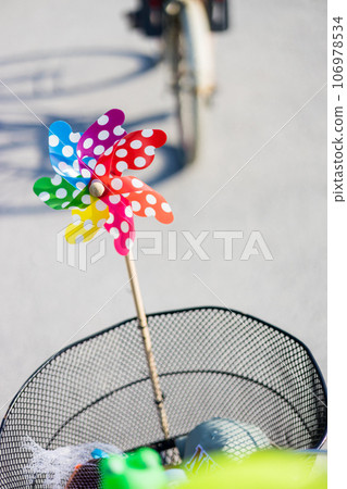 Colorful pinwheel attached to bicycle basket to entertain toddler child riding on front child seat on bike in summer 106978534
