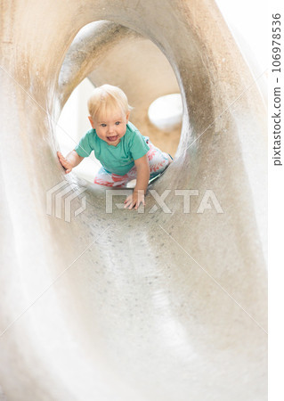 Child playing on outdoor playground. Toddler plays on school or kindergarten yard. Active kid on stone sculpured slide. Healthy summer activity for children. Little boy climbing outdoors 106978536