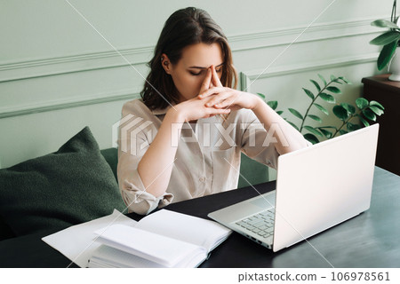 Fatigued Young Woman, Overworked and Dejected, Gazing at Computer Screen in Distress. Overwhelmed Fatigued Young Woman, Overworked and Dejected, Gazing at Computer Screen in Distress. Overwhelmed 106978561