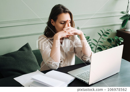 Fatigued and Dismal Young Woman Struggling with Overexertion While Staring at Computer. Weary Young Fatigued and Dismal Young Woman Struggling with Overexertion While Staring at Computer. Weary Young 106978562