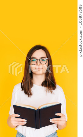 Joyful Student immersed in Reading: Cheerful Woman with Glasses Enjoying a Novel Book - Education 106978599