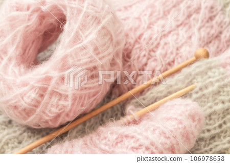 Yarn and knitting needles, top view. Grey and pink wool thread with needles. Knitting crochet. Knitted pattern. Needlework concept. Handmade pullover. Cozy warm clothing. Creativity and hobby.  106978658