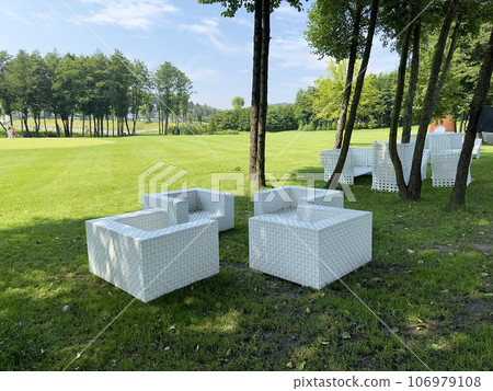 White square chairs on a green lawn in the shade under the trees where spectators watch the golf game. Rest at a tourist resort White square chairs on a green lawn in the shade under the trees where spectators watch the golf game. Rest at a tourist resort 106979108