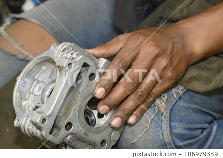 The mechanic repairing the aluminum cylinder head parts of motor cycle. 106979339