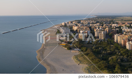 Aerial shot of sandy beach with umbrellas and town background 106979436