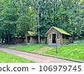 Picturesque open wooden houses, gazebos with a roof covered with green moss for relaxation, celebrations and barbecues among tall trees in the park on a sunny day. Rest in nature in the forest in the  106979745