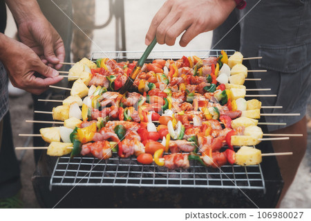 A man grilling pork and barbecue in dinner party. Food, people and family time concept. 106980027